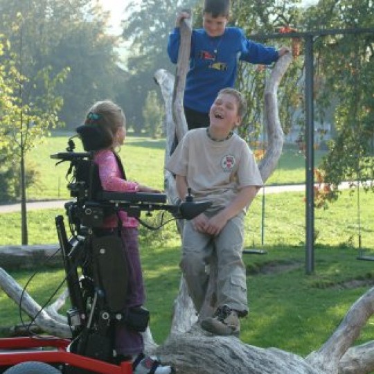 Child sitting in LEVO Combi Jr Standing Power Chair at park