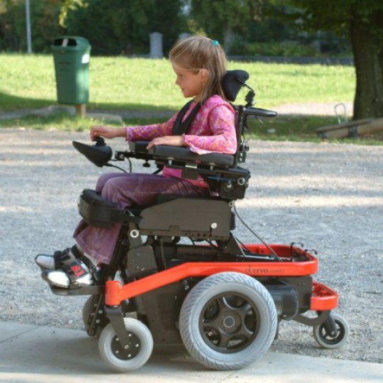 Child sitting in LEVO Combi Jr Standing Power Chair at Park